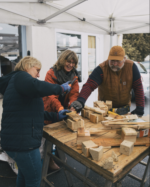 Trois personnes autour du bois entrain de faire un atelier sur la découverte de la construction de palette